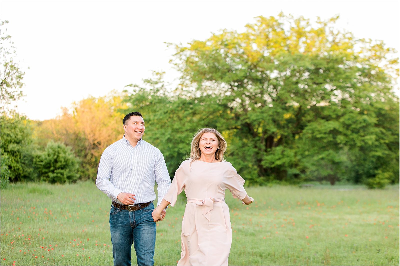 An engaged couple running in a field laughing near Fort Worth, Texas 