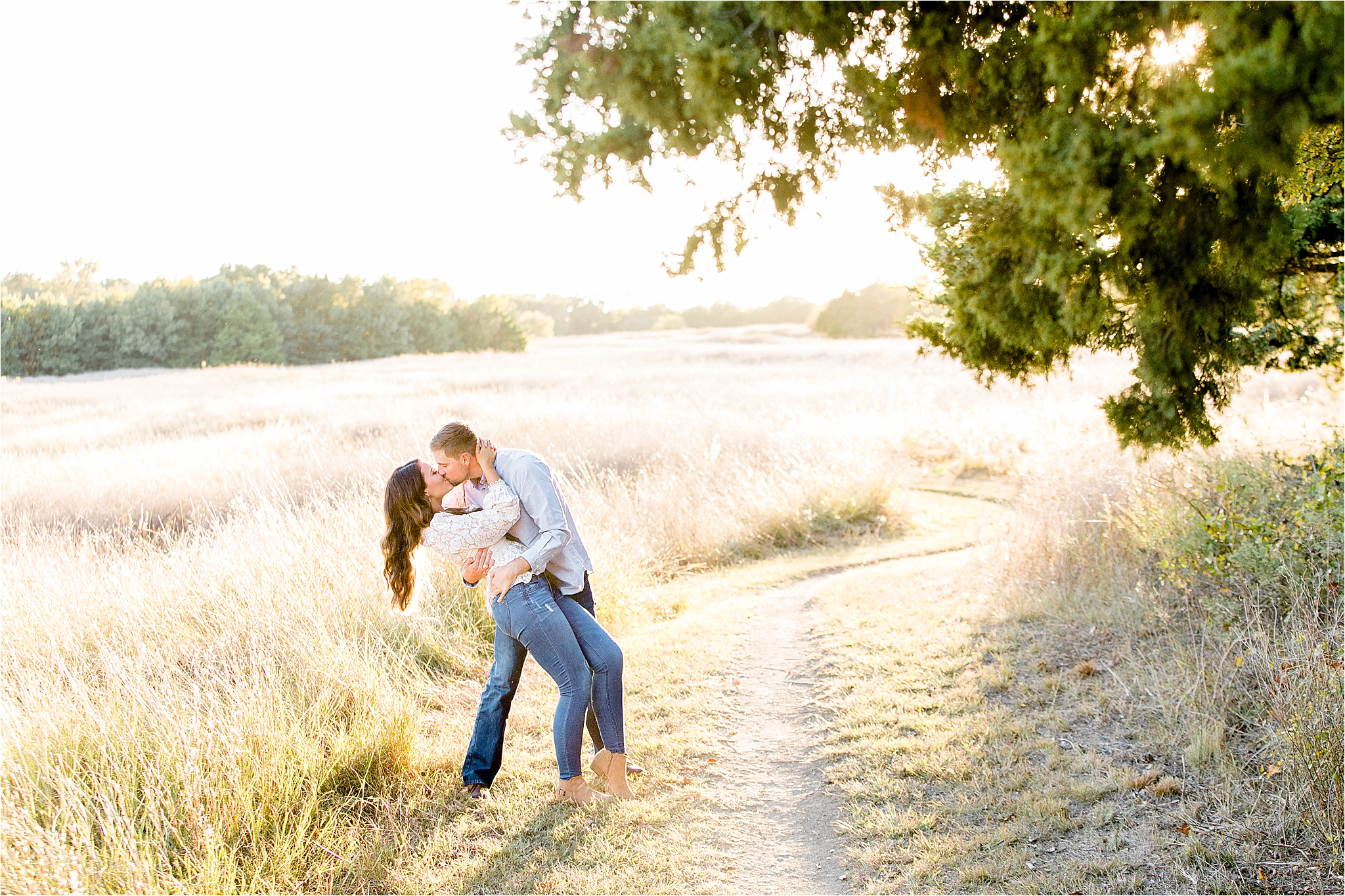 An engaged couple dips and kisses in a sunny field during their fall engagement session in McKinney, Texas 