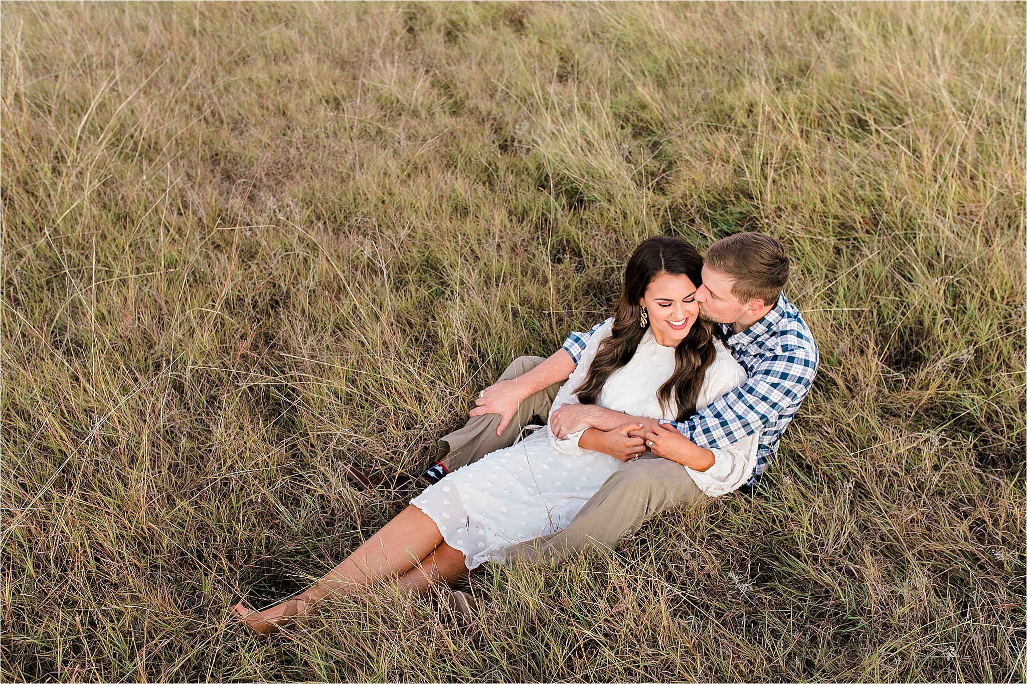 An arial shot of an engaged couple sitting in a field and embracing during their fall engagement session in McKinney, Texas