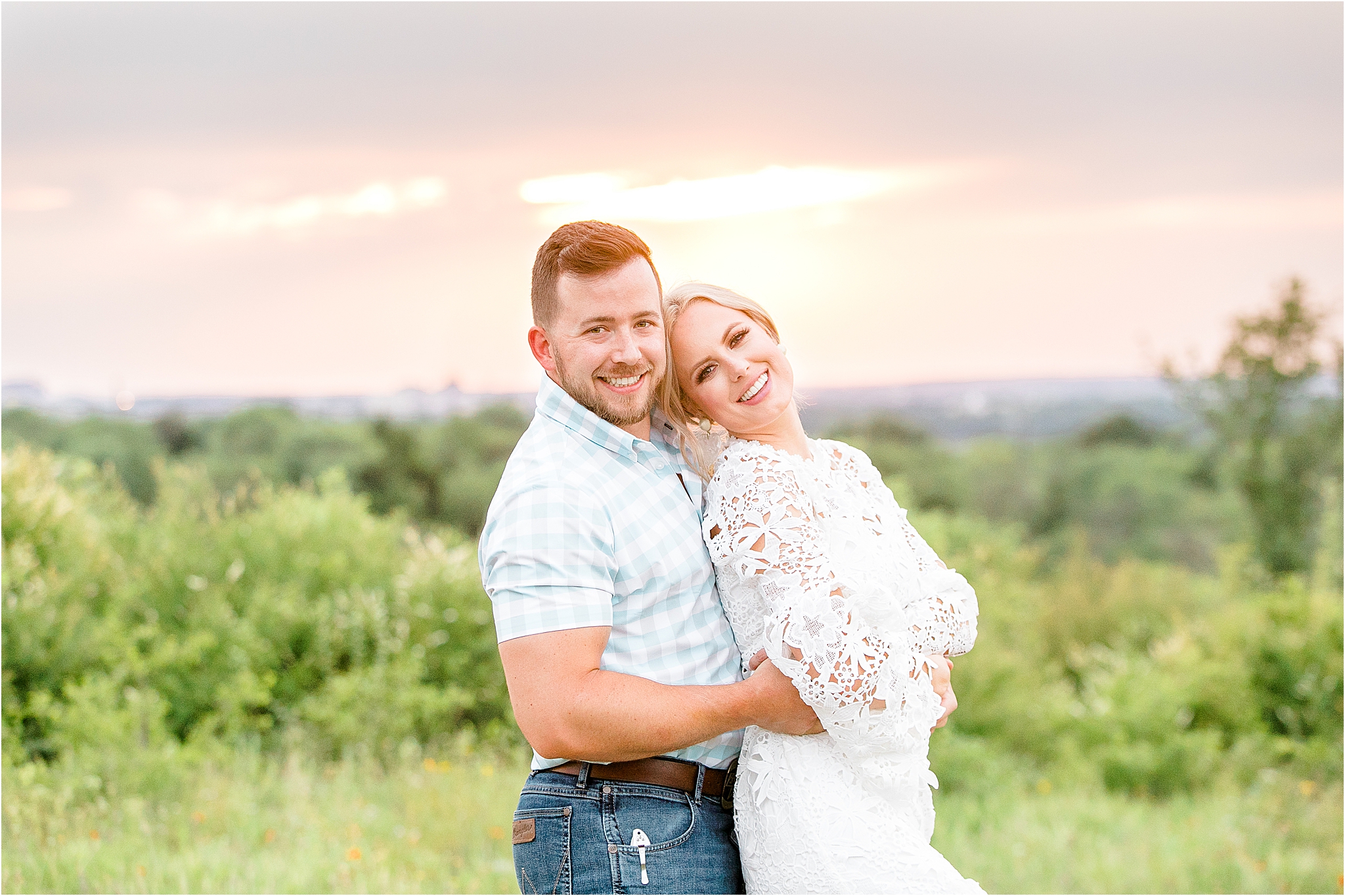 A bride to be spins into her grooms arms while they are dancing in front of greenery and a colorful sunset during their fort worth engagement session at Tandy Hills Nature Preserve 
