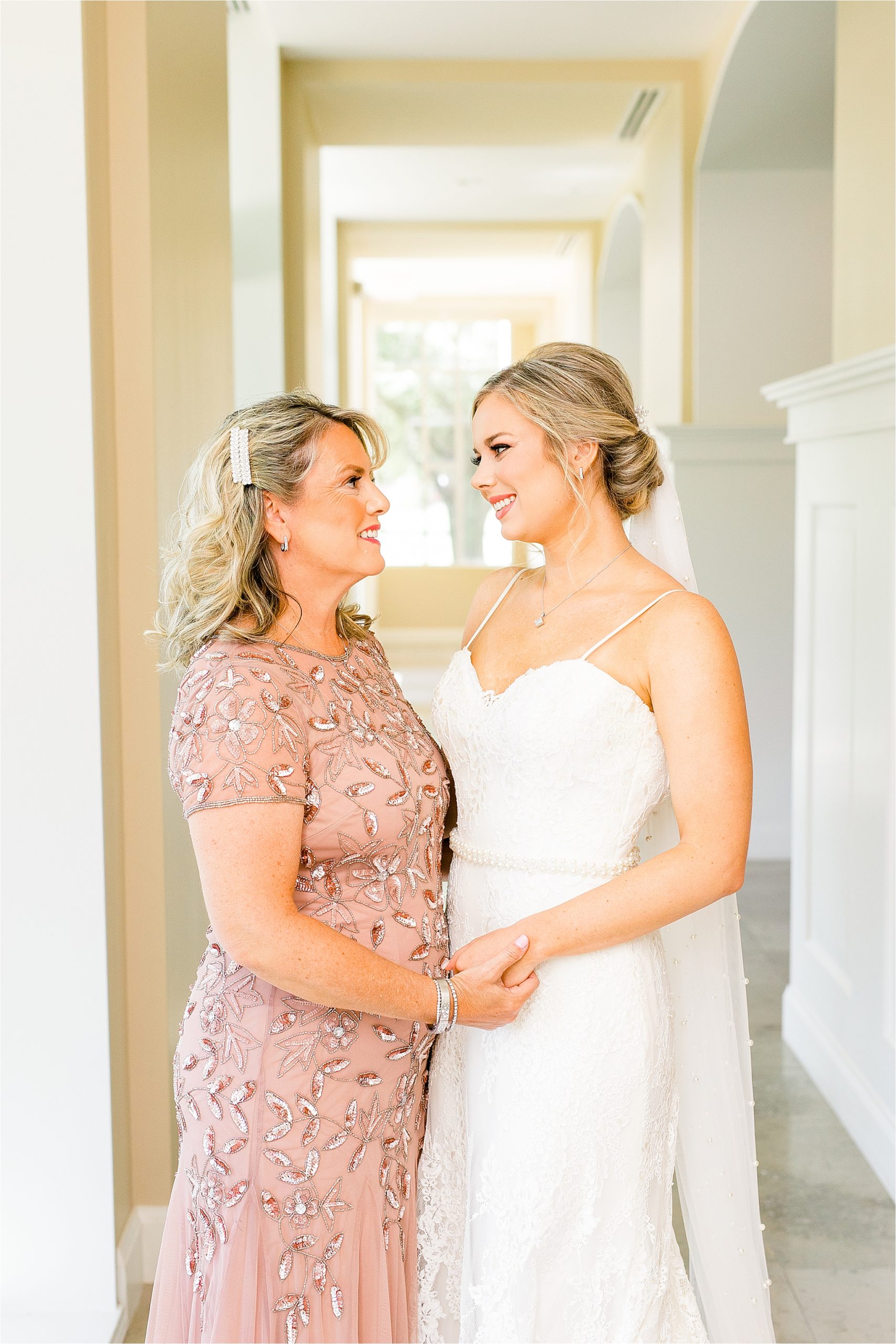 A bride and her mom hold hands and look at each other moments before she walks down the aisle for her classic prestonwood chapel wedding in Plano, Texas 
