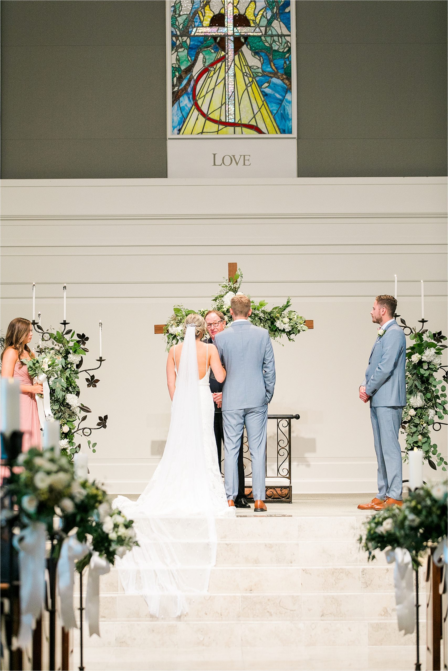 A bride and groom face their minister as the veil flows down the stairs at their Prestonwood Chapel ceremony in Plano, Texas 