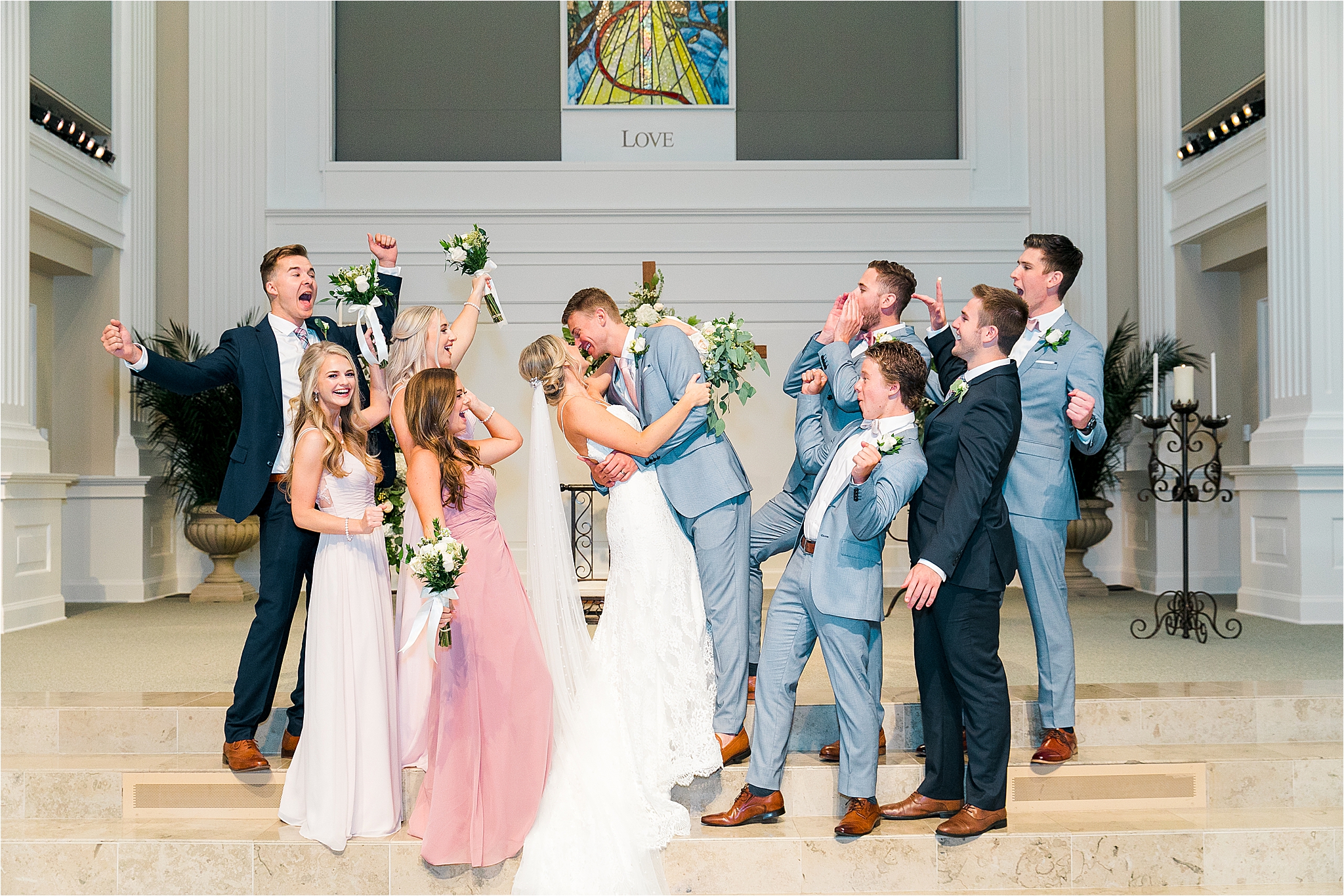 A bridal party cheers on the married couple as they share a kiss during wedding portraits at Prestonwood Chapel 