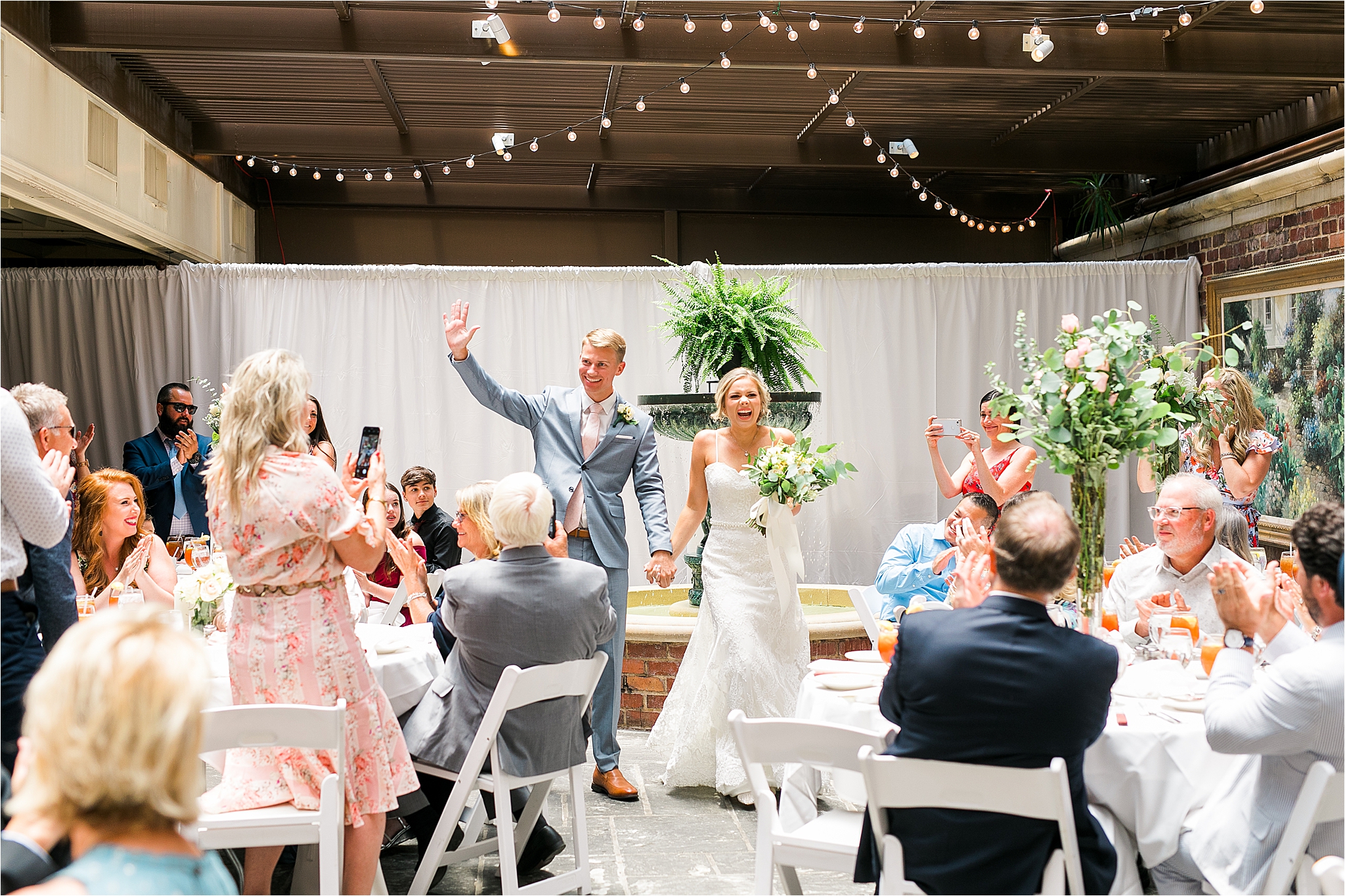 A bride and groom happily enter their III Forks Dallas Reception Venue while their guests cheer them on