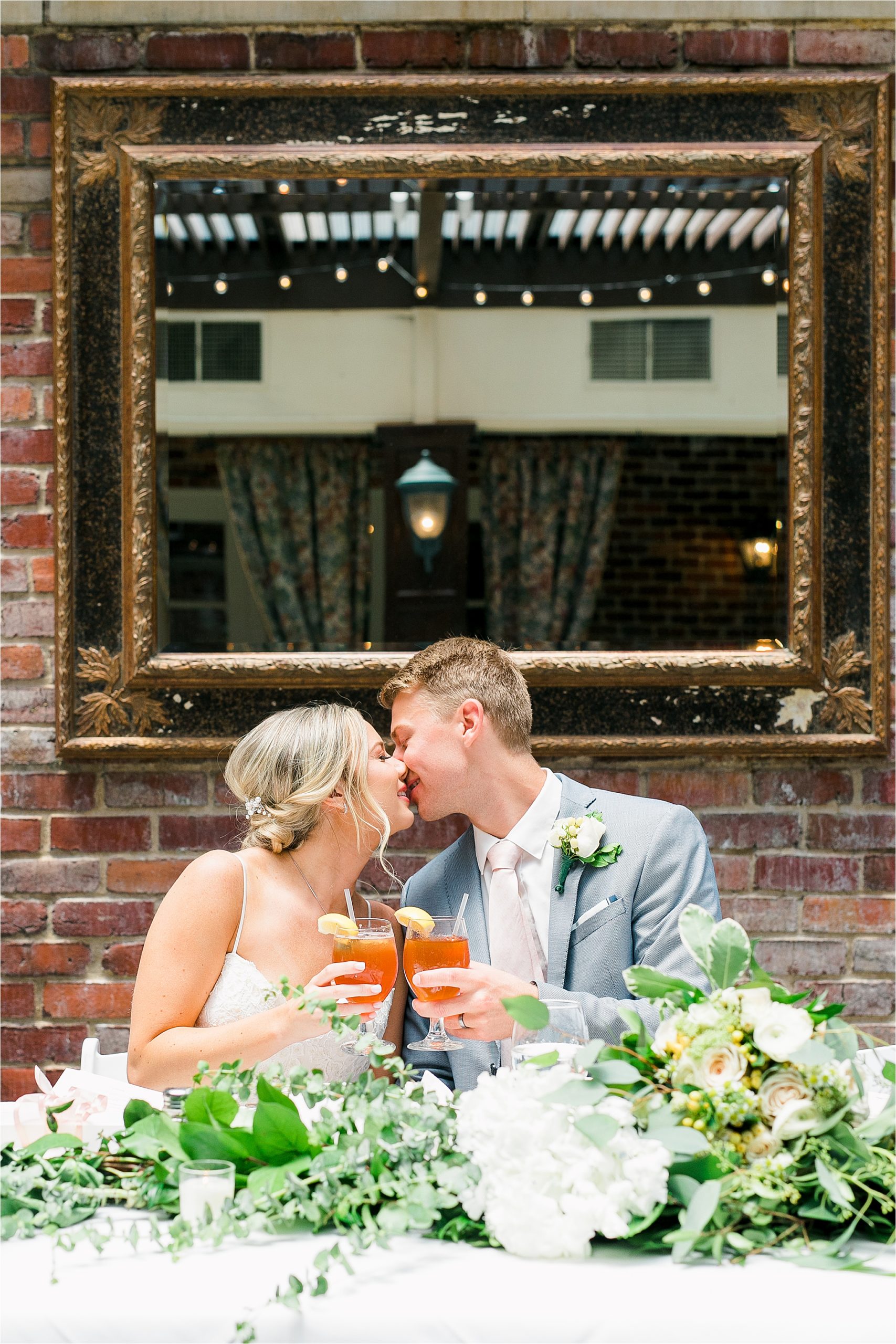 A bride and groom share a kiss at their head table during their garden reception at III Forks in Dallas, Texas 
