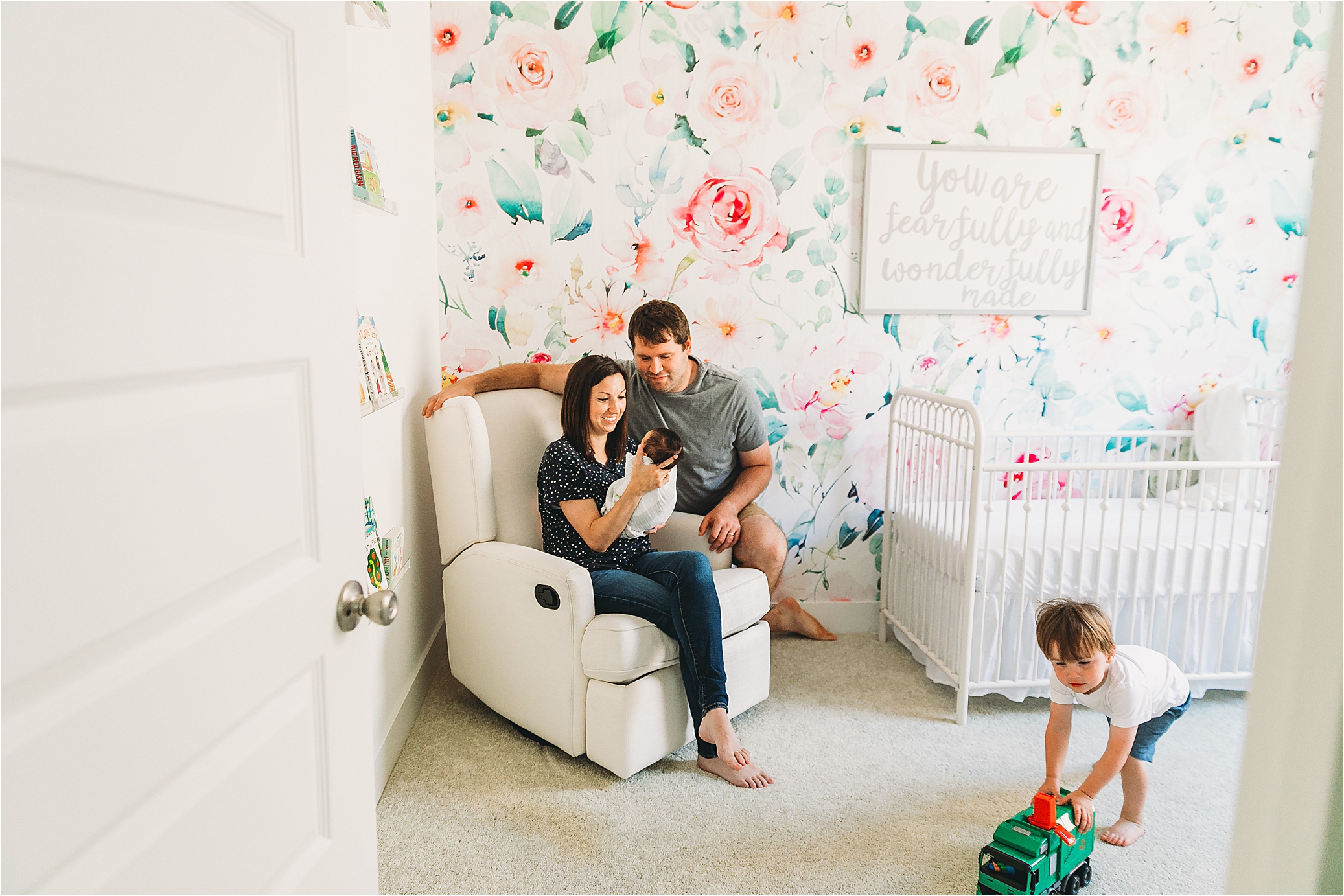 A family looking holding their newborn baby girl while big brother plays with his dump truck during their in home Dallas Lifestyle newborn session 