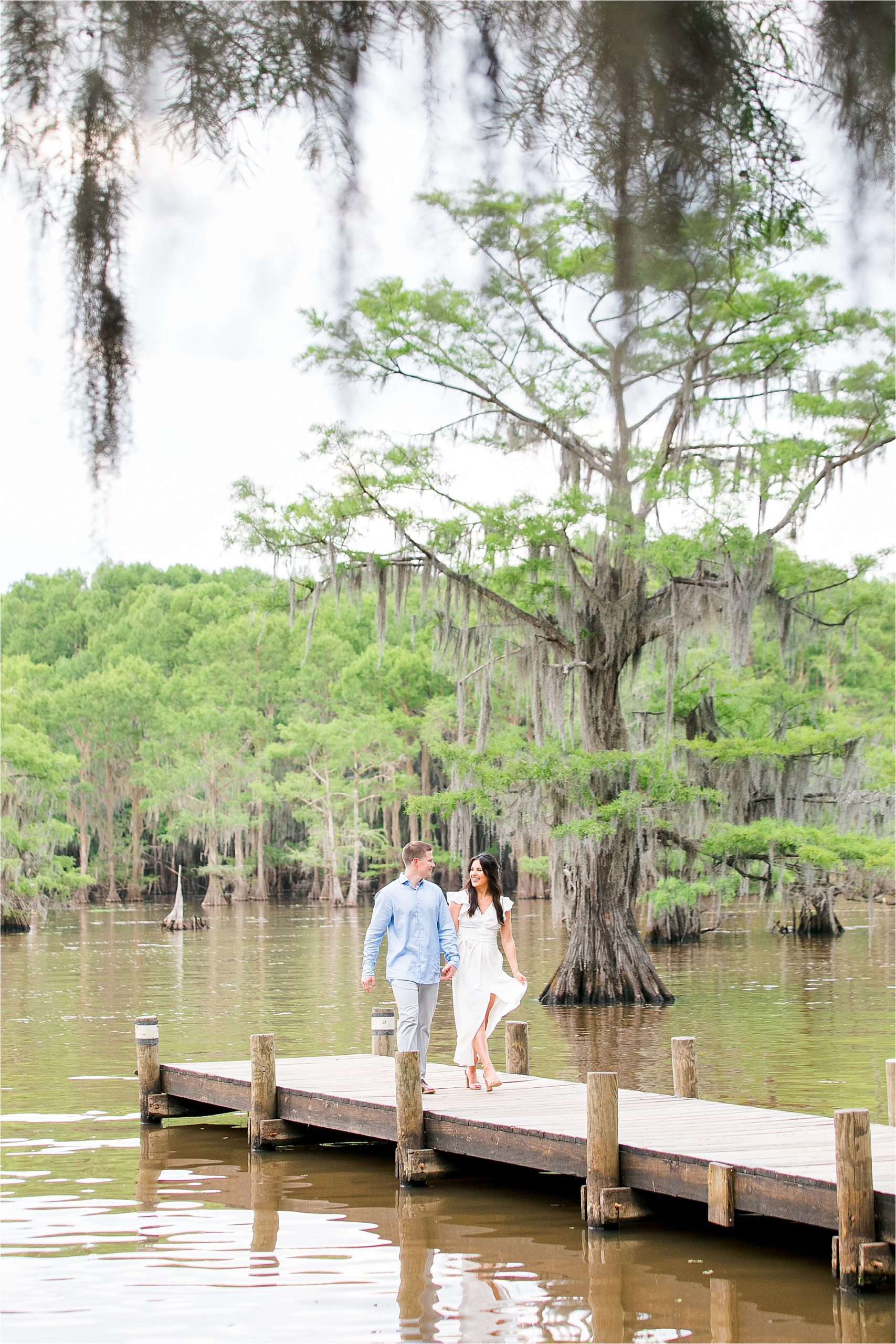 A couple holding hands on the docks at Caddo Lake in East Texas during their Destination Engagement session