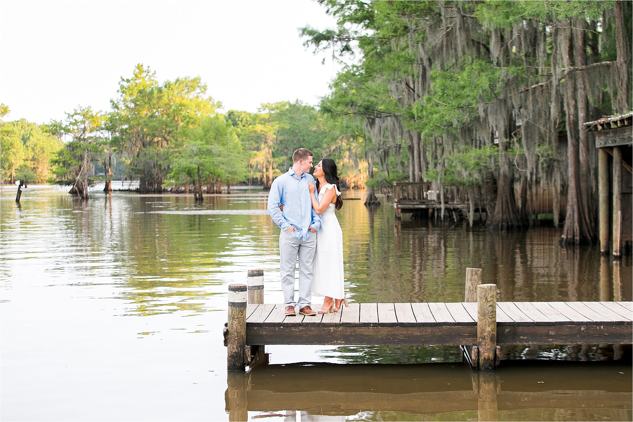 A couple romantically embraces on a dock at Caddo Lake State Park in East Texas during their engagement session 