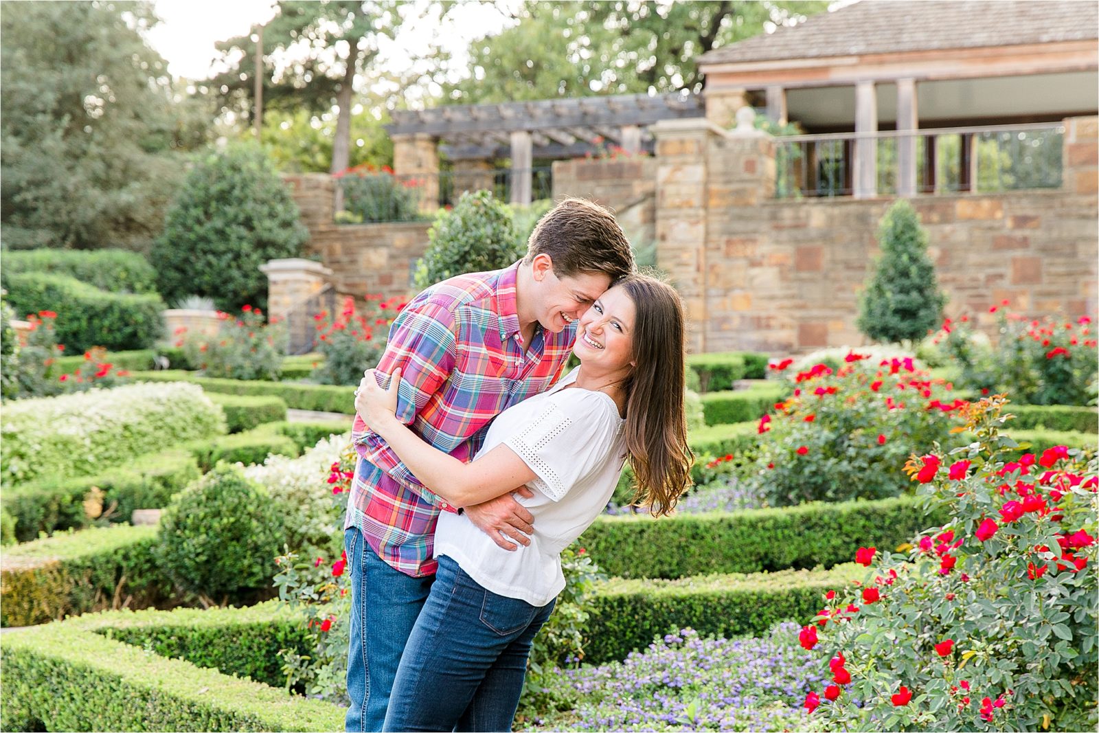 A playful couple embraces during their fall engagement session at The Fort Worth Botanic Garden.