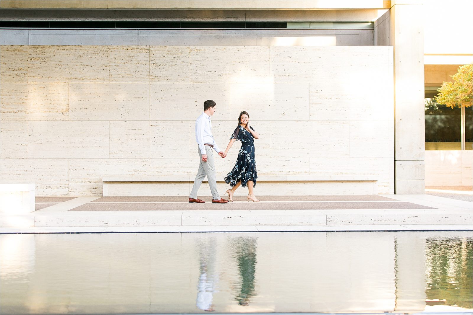 An engaged couple holding hands in front of a reflection pond at The Kimball Art Museum in Fort Worth, Texas 