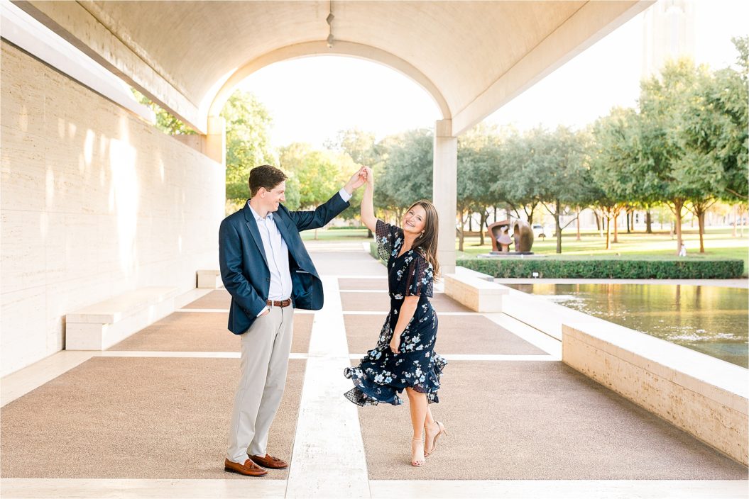 A bride to be looks back at the camera as her fiance spins her during their Fort Worth Engagement Session at The Kimball Art Museum. 