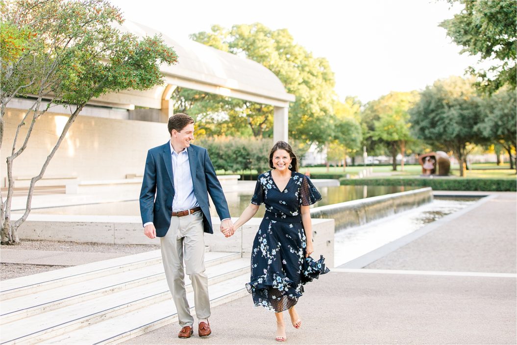An engaged couple runs toward the camera holding hands during their engagement session with DFW Photographer Jillian Hogan at The Kimball Art Museum in Fort Worth, Texas. 