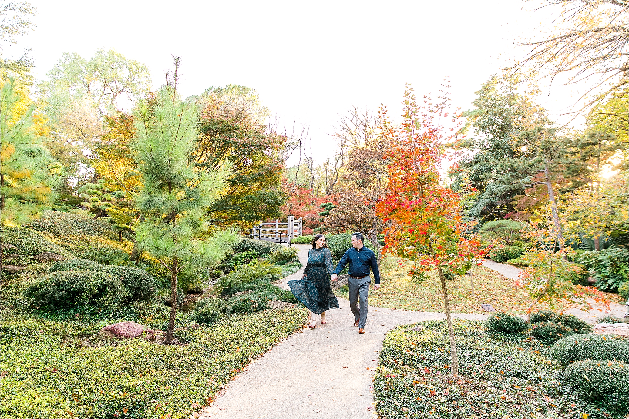 A couple runs on a sidewalk at The Japanese Gardens on a sunny, fall day at The Fort Worth Botanic Garden 