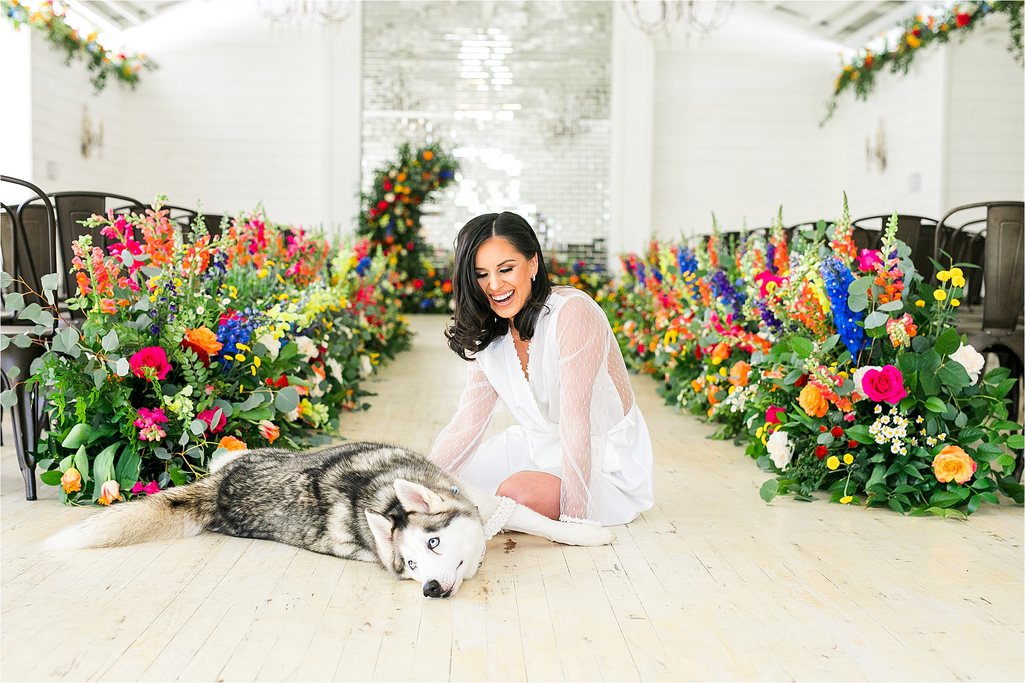 A bride loves on her husky in front of a colorful floral display at Pinway Farms with Hill Country Wedding Photographer Jillian Hogan 