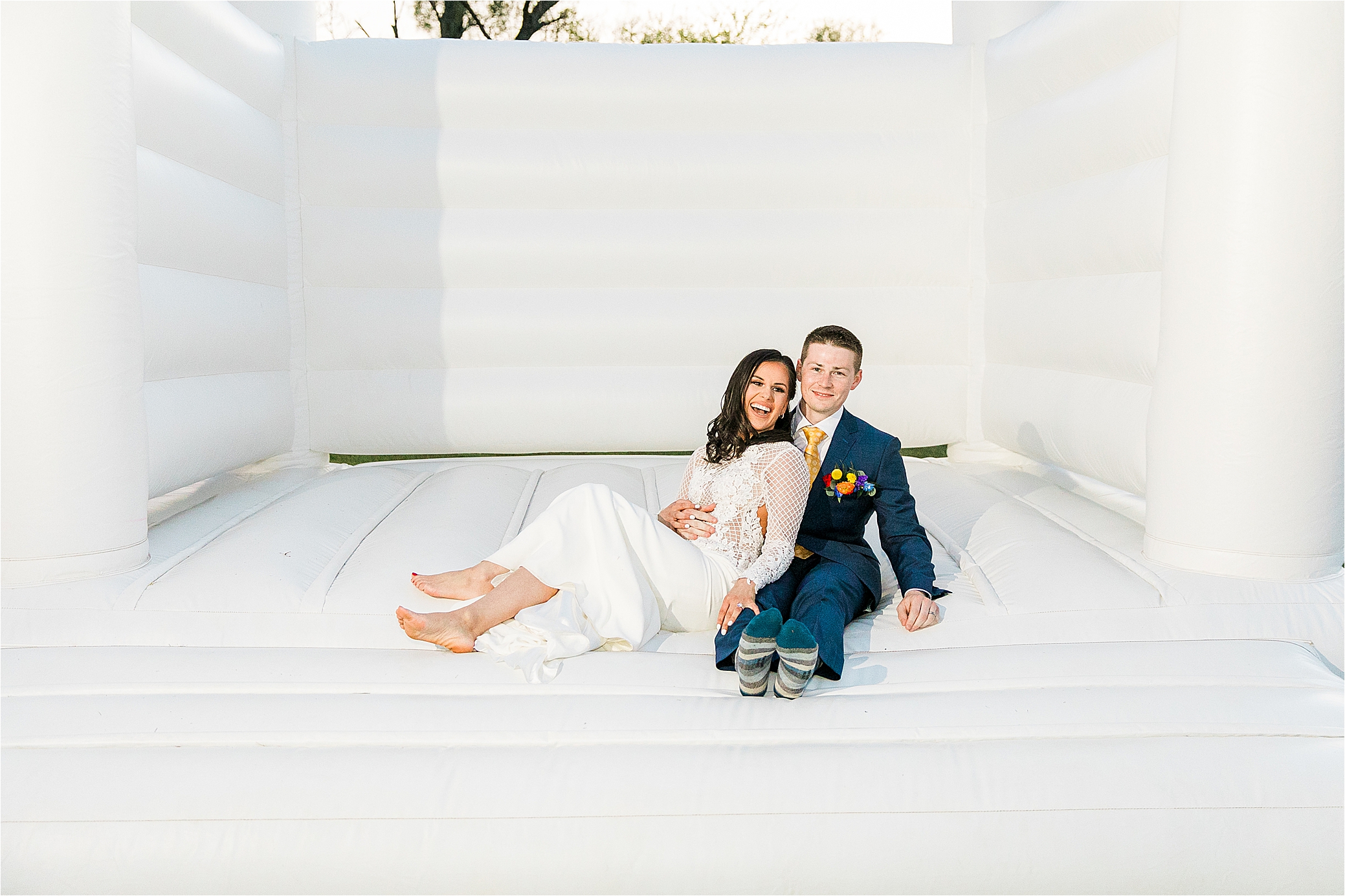 A couple lounges in a bounce house on their wedding day at Pineway Farms