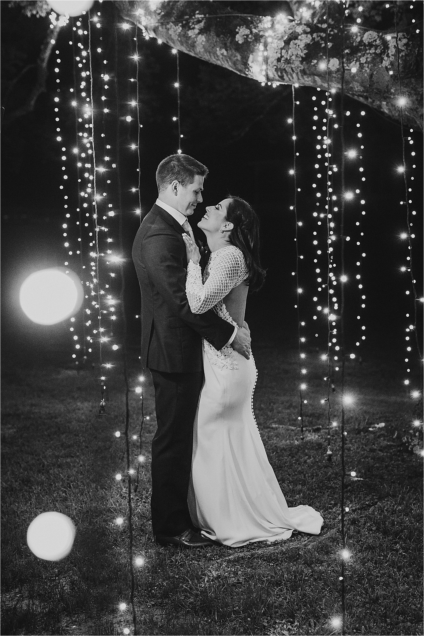 A couple embraces under the twinkle lights at their PIneway Farms wedding with Hill Country Wedding Photographer Jillian Hogan 