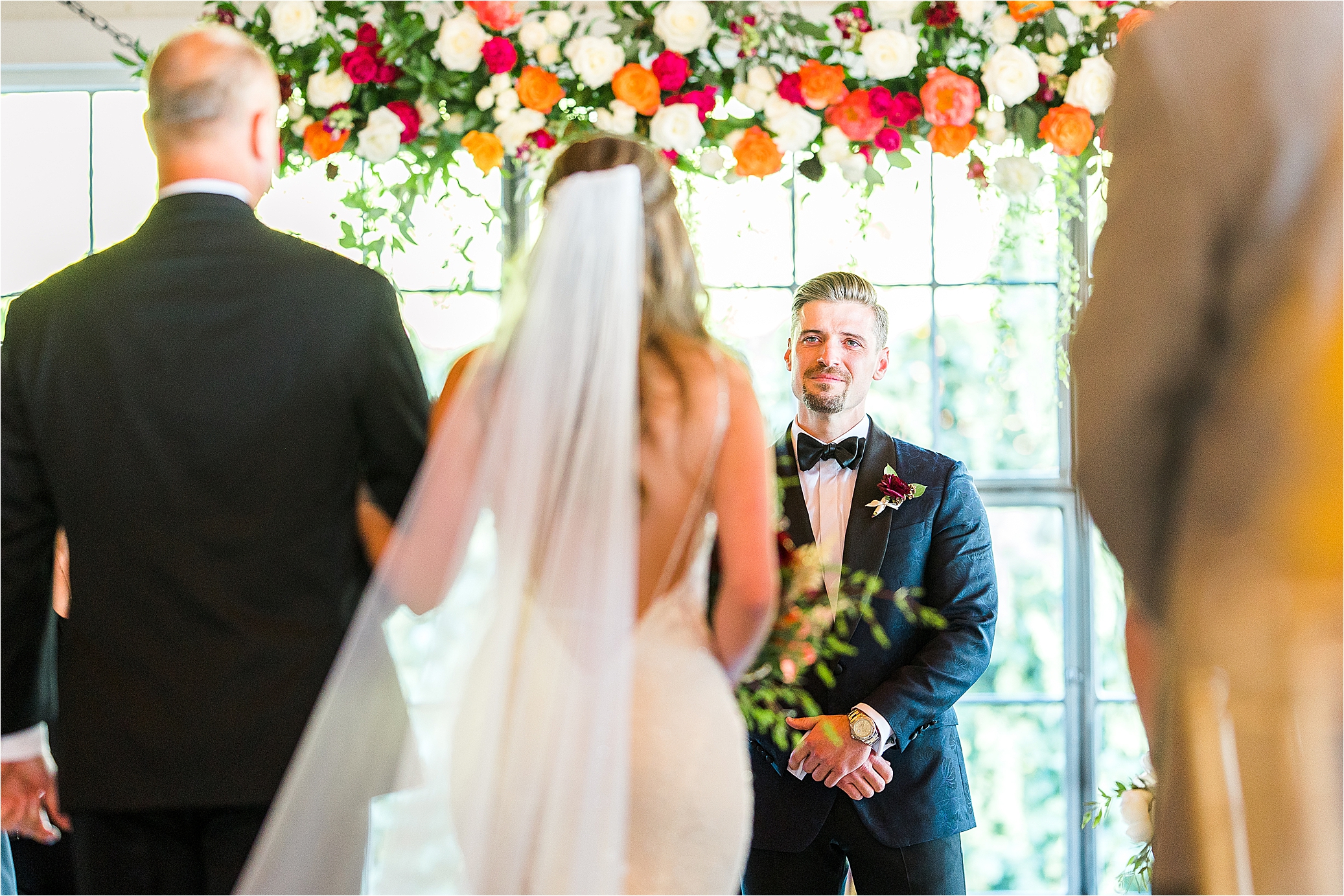 A groom very emotionally smiles at his bride as they make eye contact during their wedding ceremony at HIckory Street Annex 
