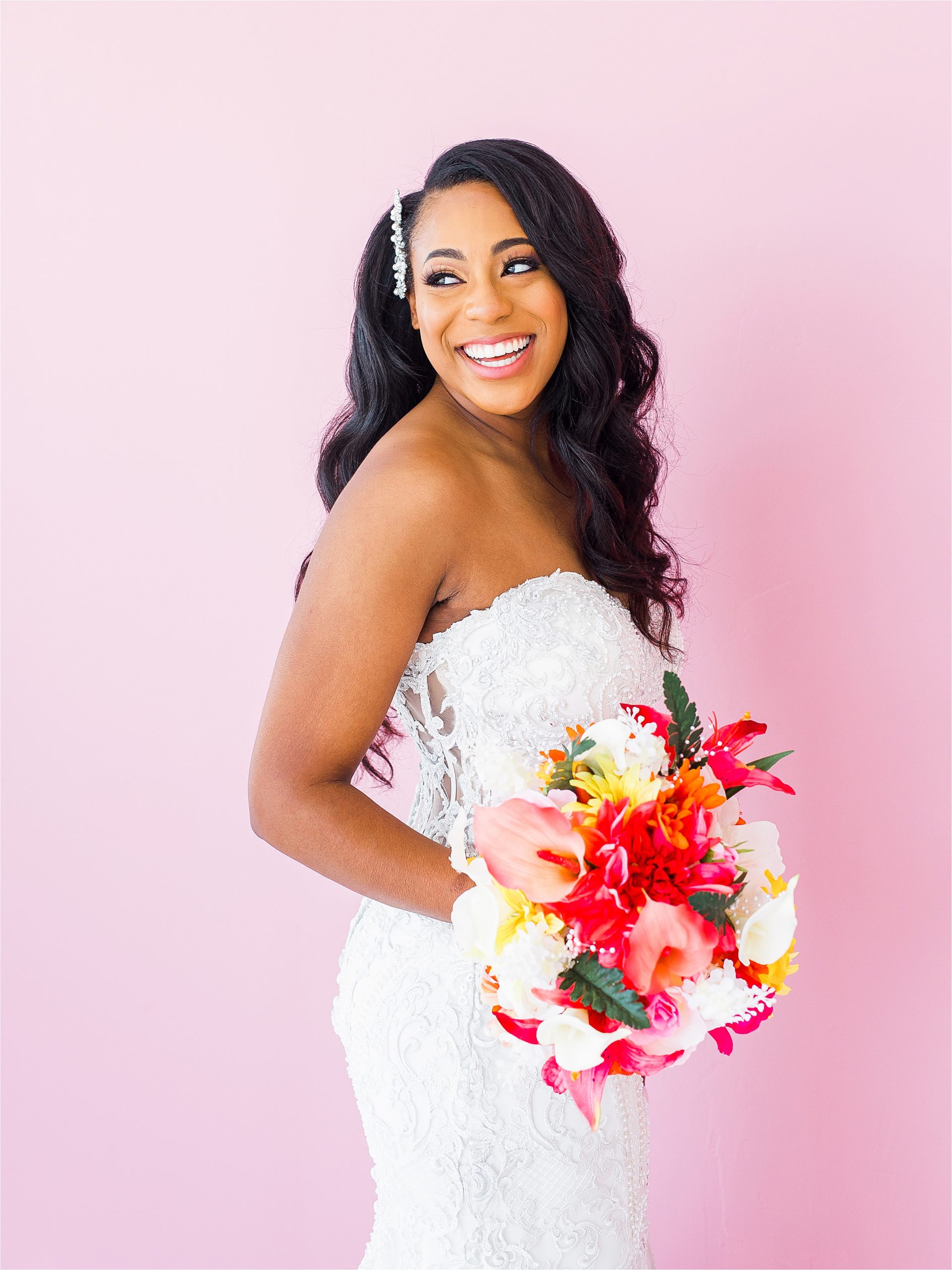 A beautiful bride laughs over her shoulders in front of bright pink backdrop during her San Antonio Studio Bridal Session 