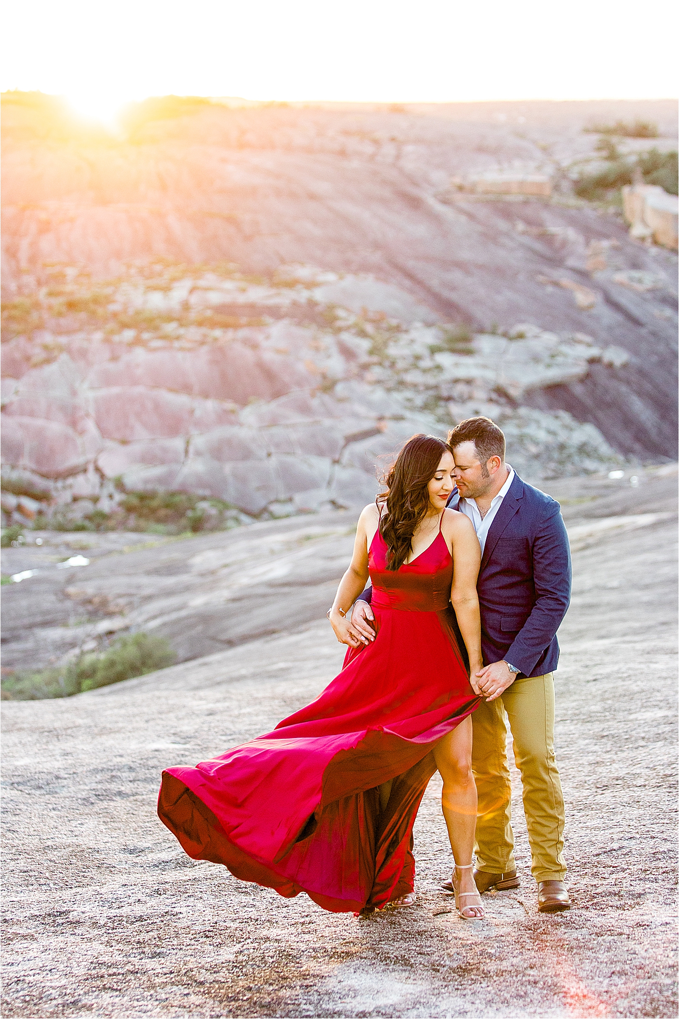 A couple holds each other close in front of the sunset at Enchanted Rock during their Hill Country Engagement Session with Photographer Jillian Hogan 