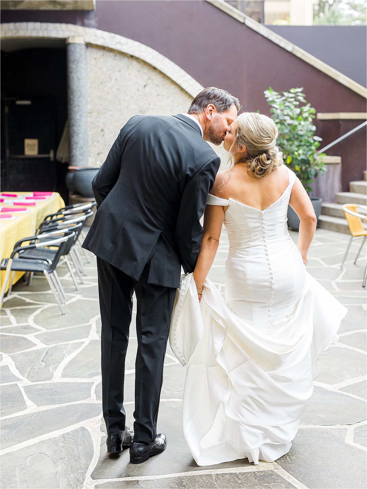 A couple shares a kiss as we see them from behind on the Hotel Valencia Patio as they head to their wedding ceremony.
