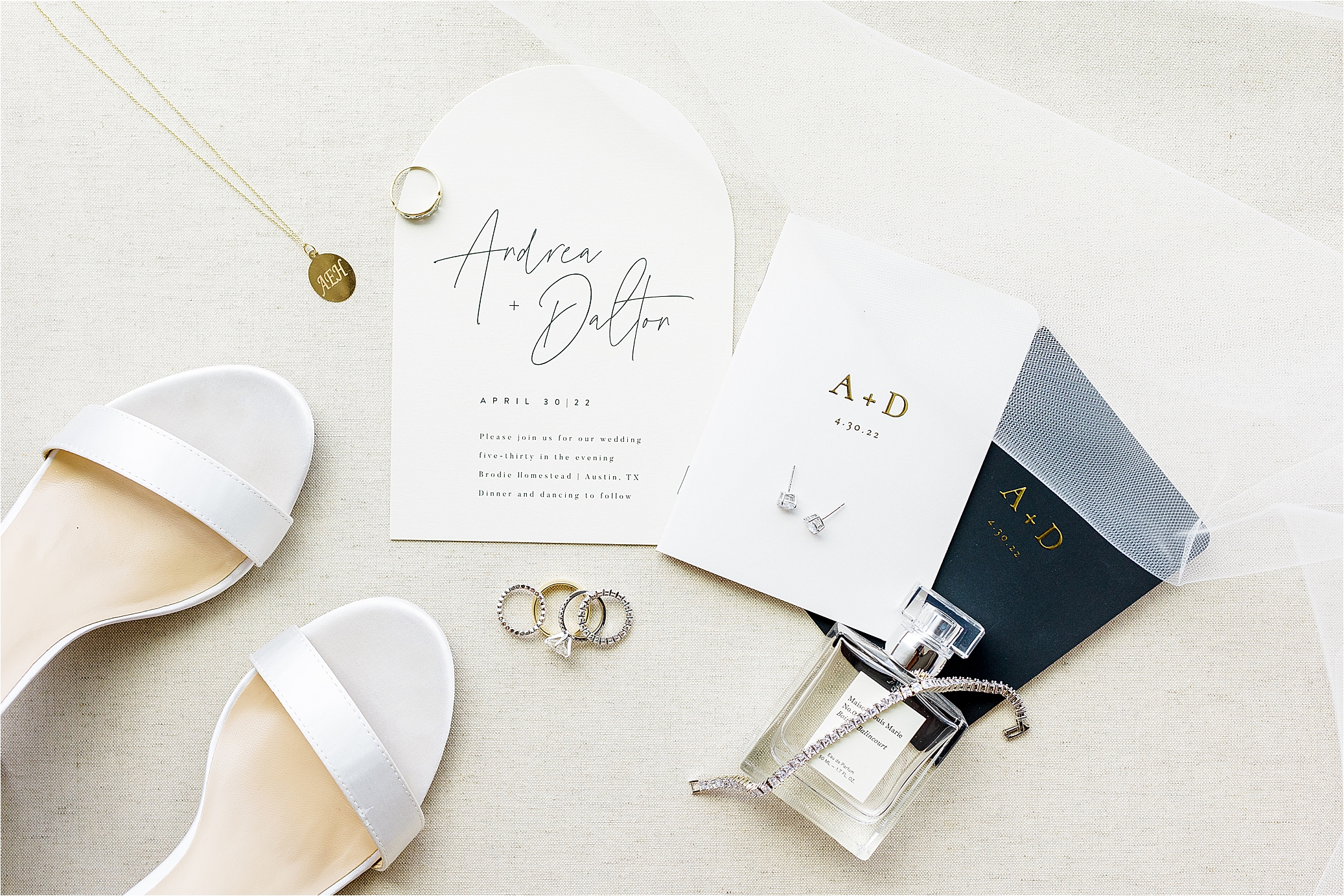A photo of black and white bridal details, perfume, white shoes, gold necklace and an invitation with script type and a veil in corner for an Austin, Texas Wedding