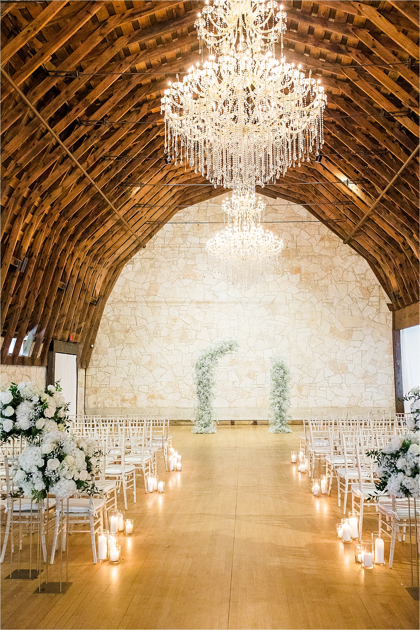 Wedding Venue with a white flower arch, chandeliers, candles in a barn type setting at Brodie Homestead in Austin, Texas