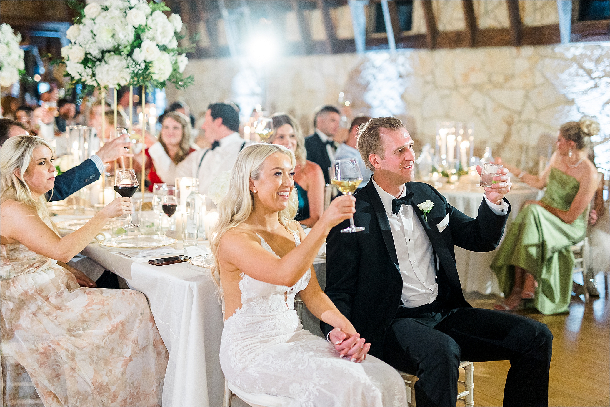 A bride and groom hold their drinks and cheers as they hold hands at their wedding reception in Austin, Texas