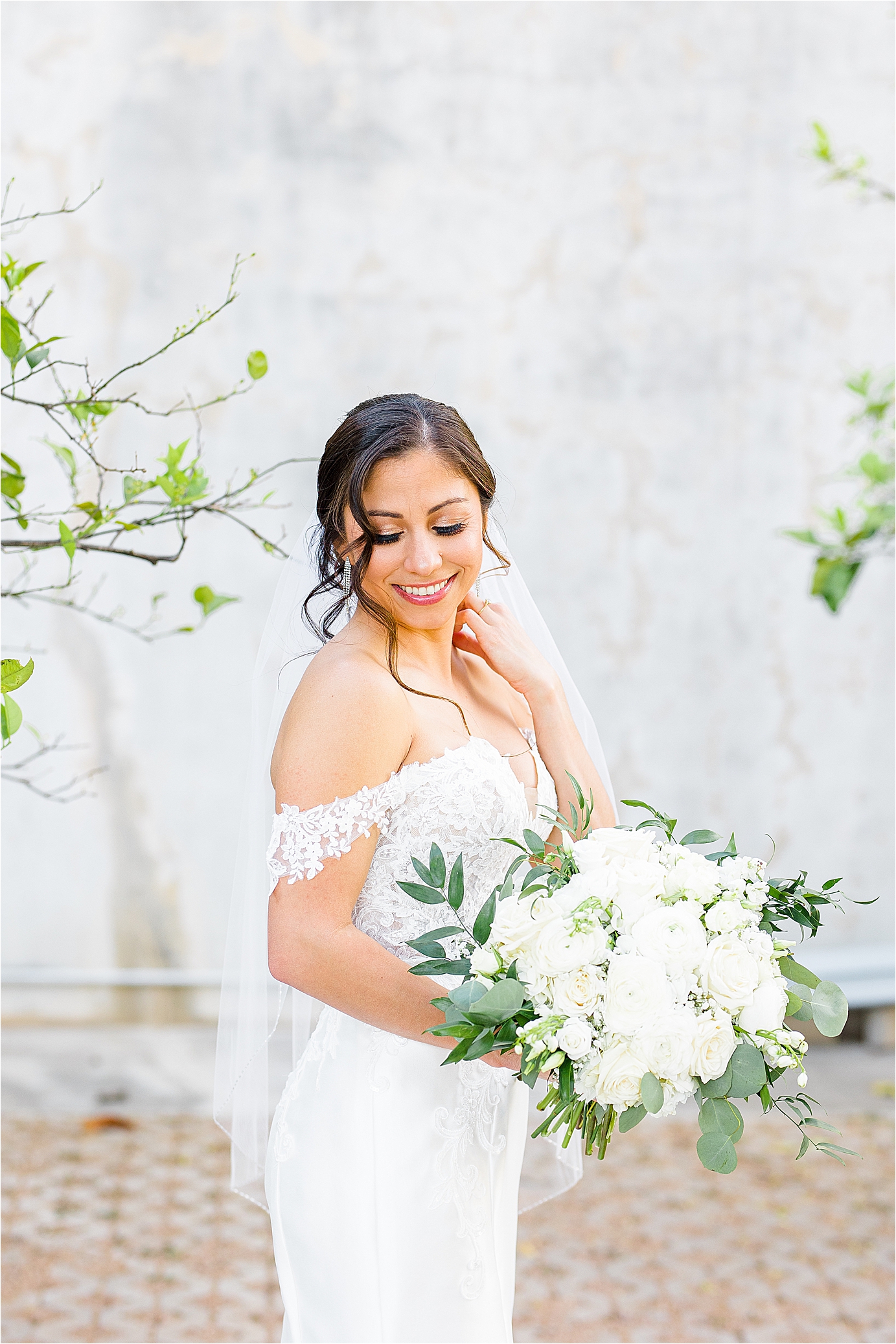 A bride looks over her shoulder holding white bouquet at San Antonio Botanical Garden for her Bridal Portraits with Jillian Hogan Photography 