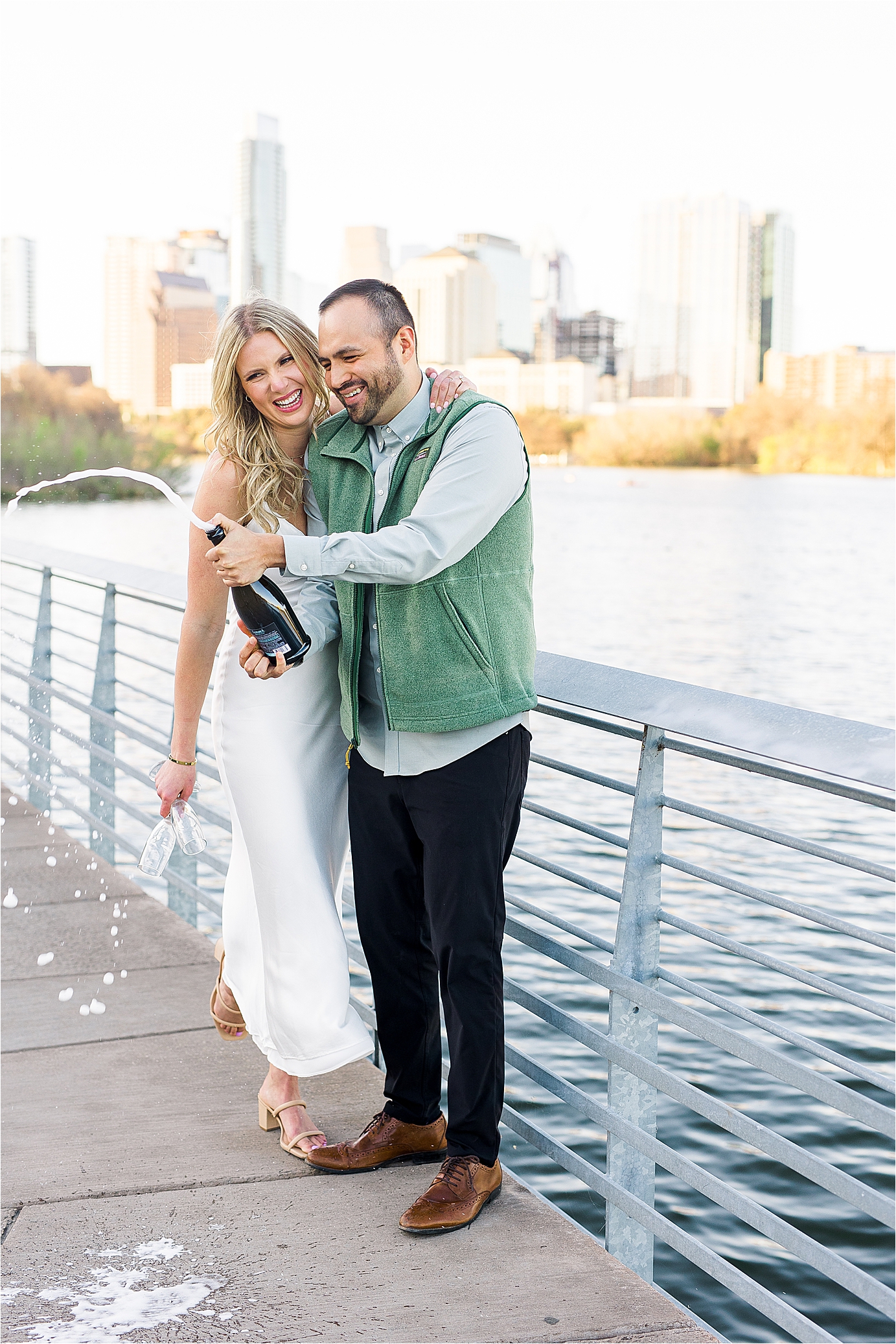 A couple pops a bottle of champagne on Austin boardwalk to end their engagement session