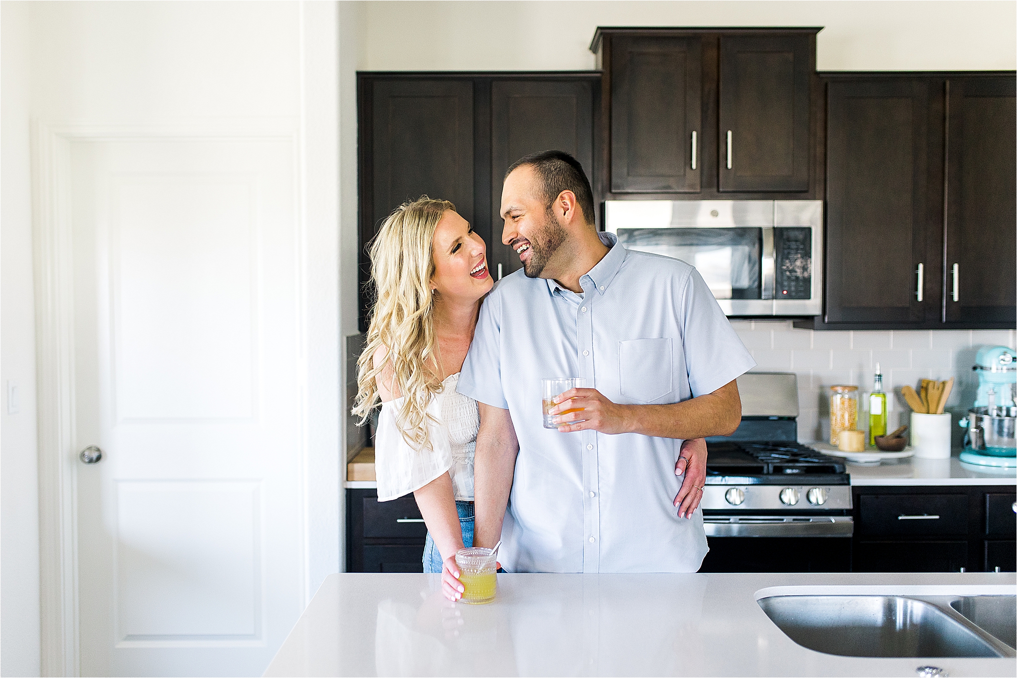 A couple laughs at each other in their kitchen during their at home lifestyle engagement session in Austin, Texas