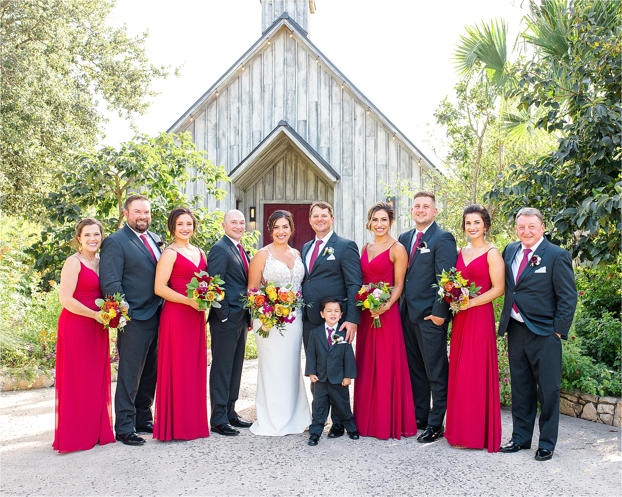 A bridal party with colorful bouquets smiles at the camera for photos at Paniolo Ranch in Boerne, Texas