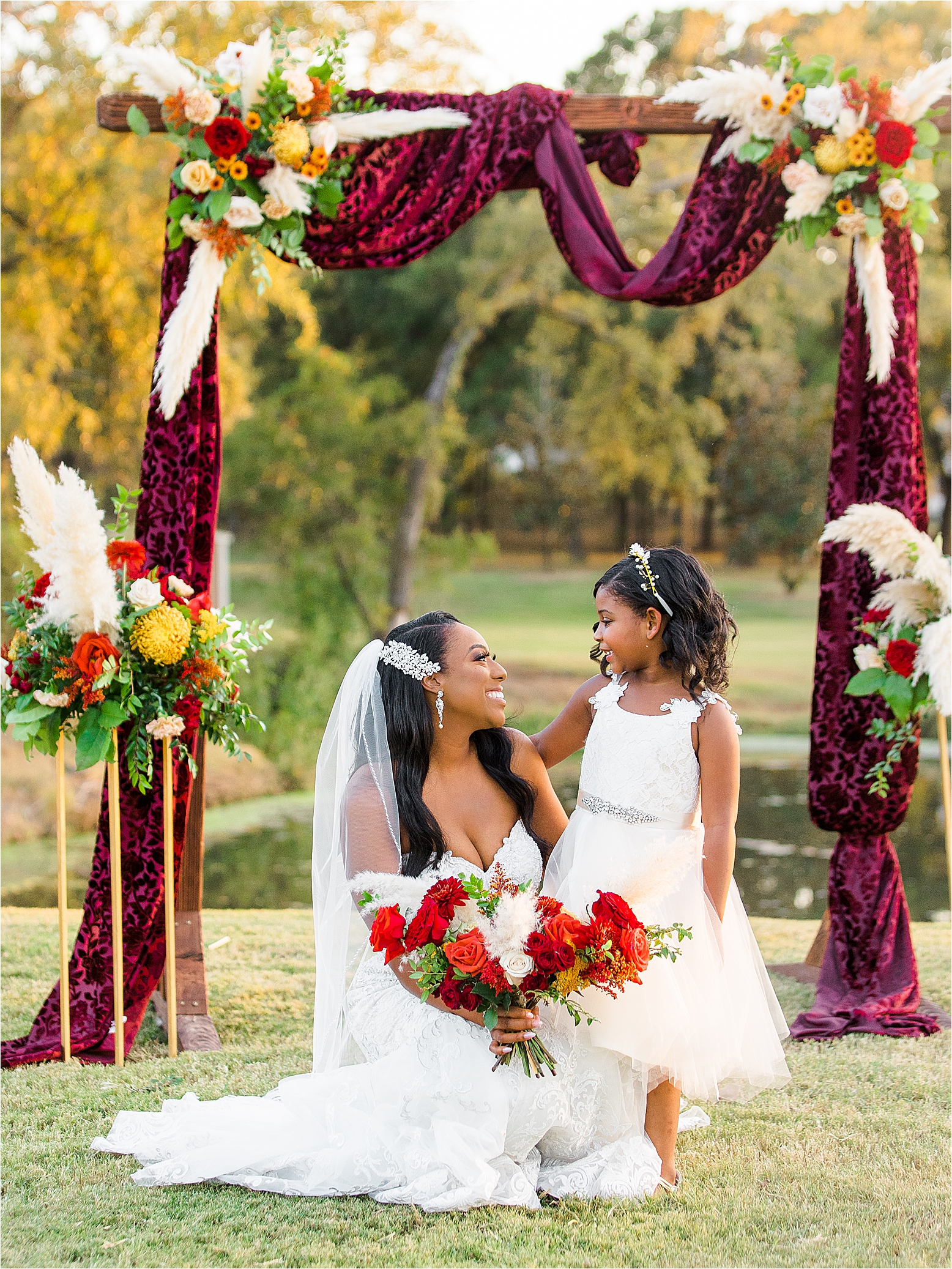 A bride and her flower girl smile at each other under a colorful arch at The Milestone in Boerne, Texas 