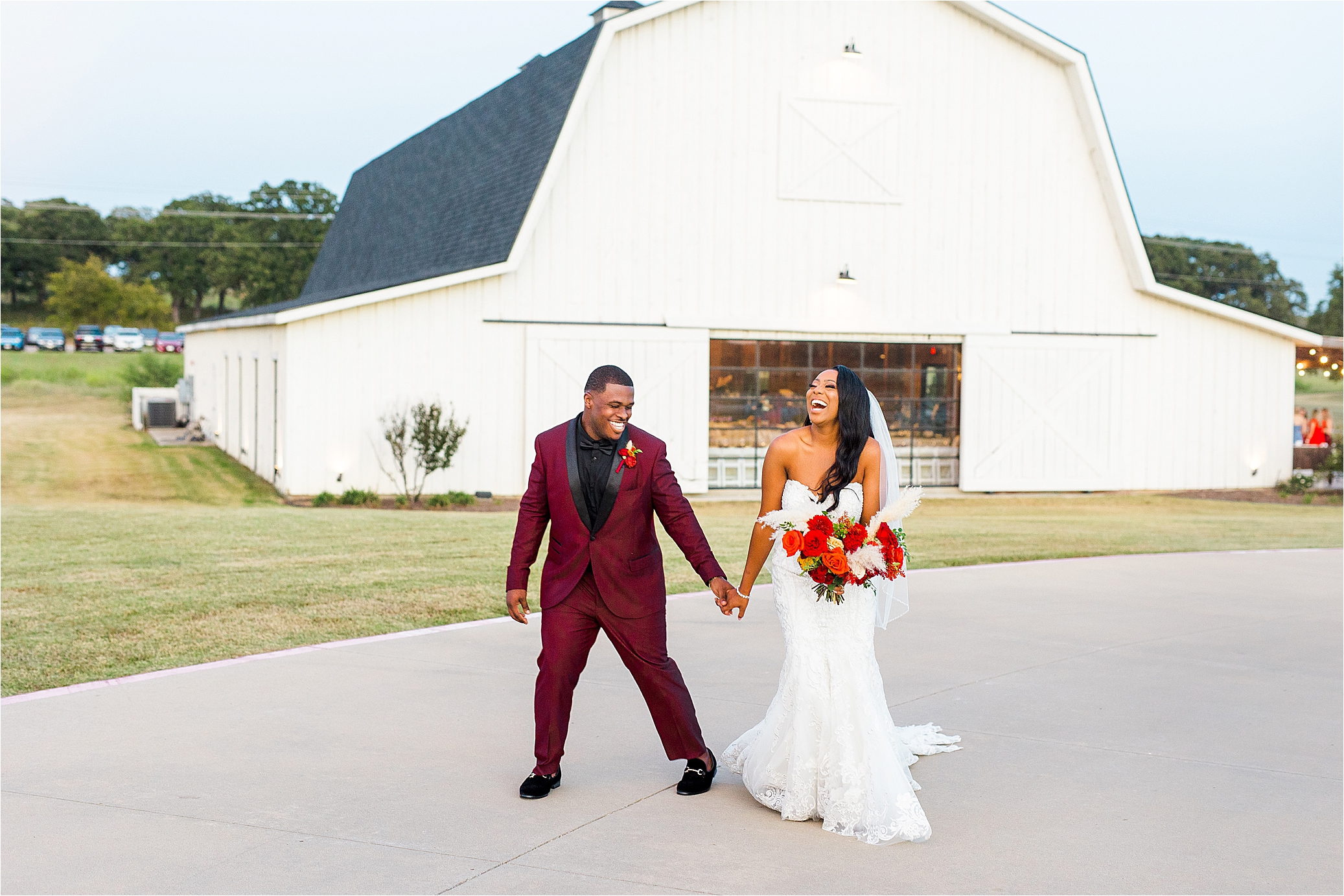 Newlyweds hold hand and laugh hysterically in front of white barn at Milestone by Boerne Wedding Photographer Jillian Hogan 