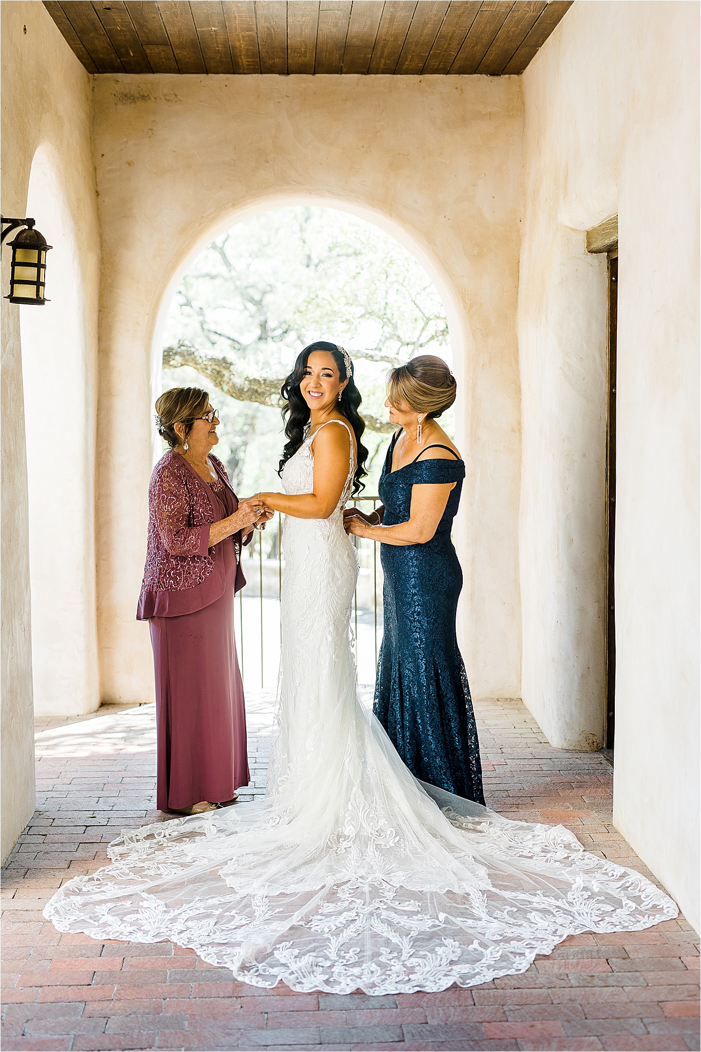 A bride shares a moment with her mom and grandmother as she puts on her wedding dress at Lost Mission in Texas Hill Country 
