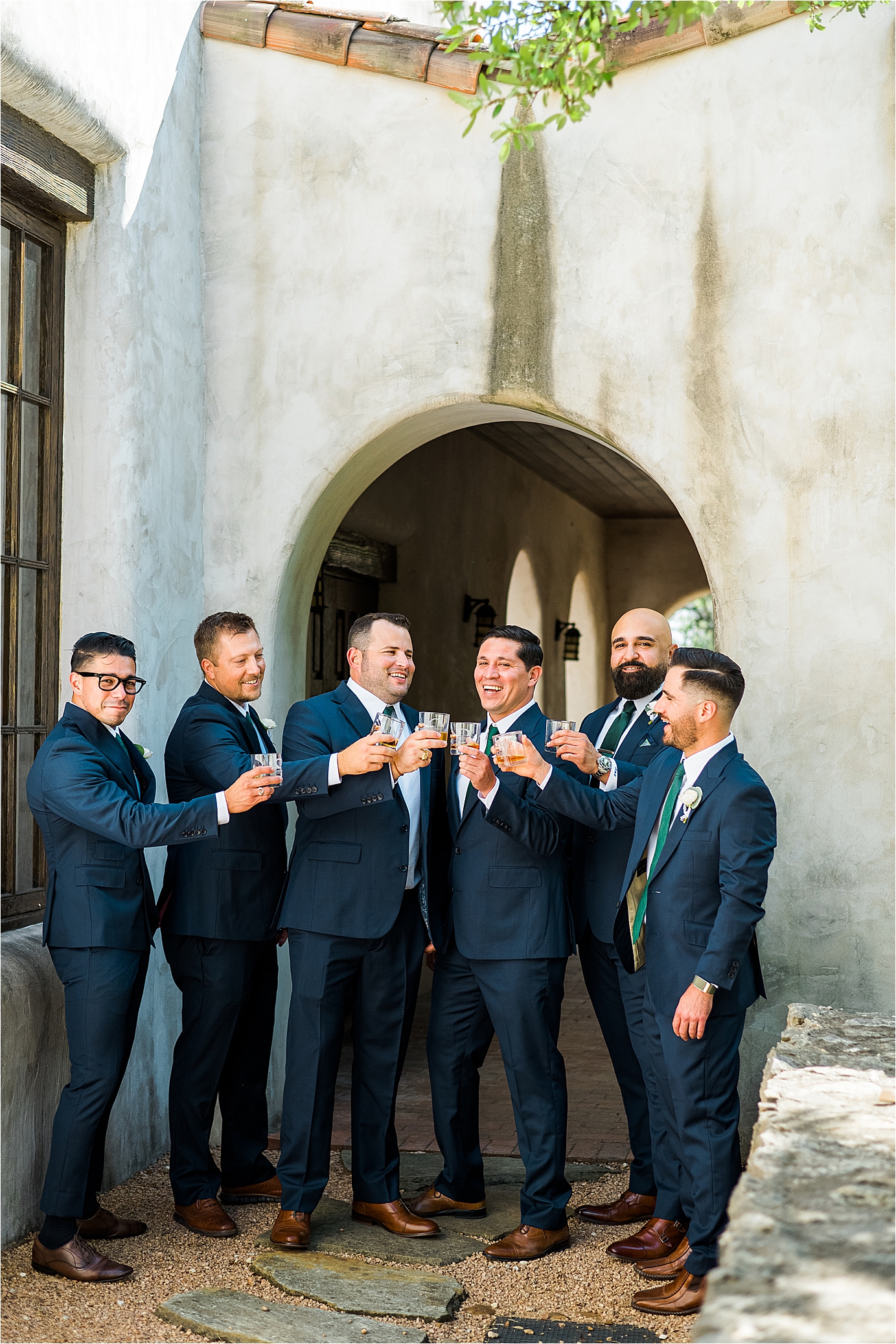 A groom laughs and cheers with his groomsmen on his Lost Mission Wedding Day