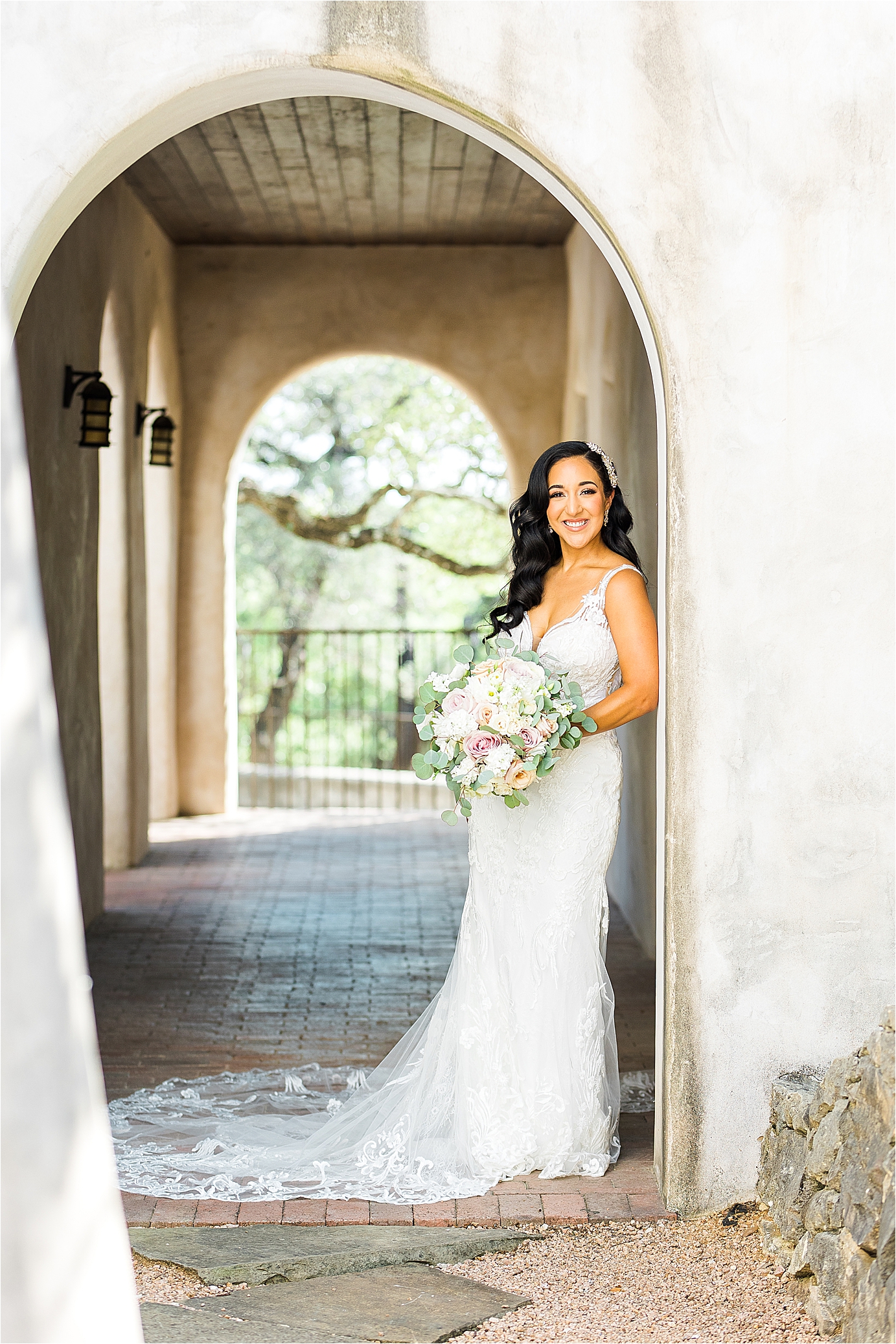 A bride poses in front of a beautiful arch with her bouquet at Lost Mission with Texas Hill Country Wedding Photographer Jillian Hogan 