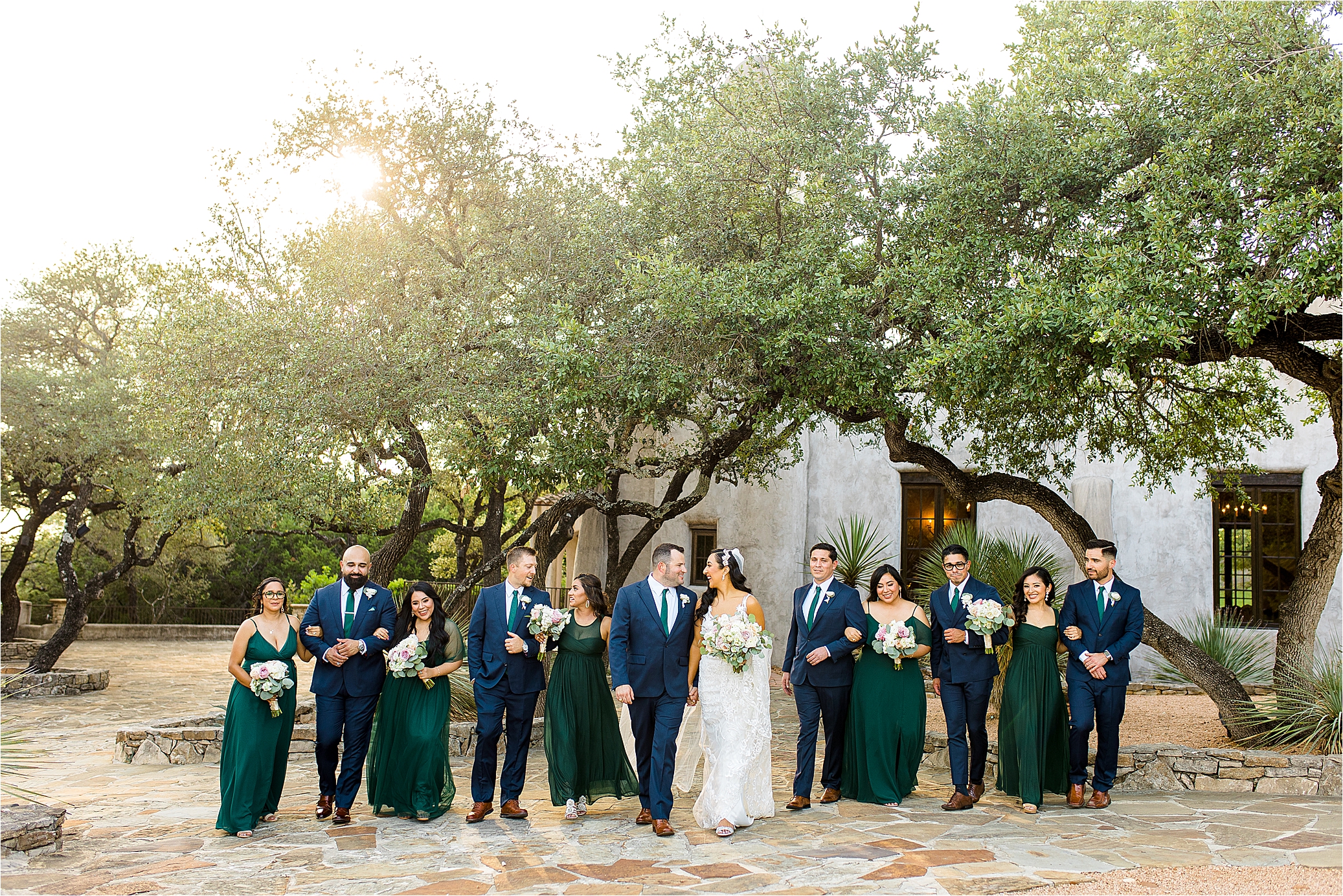 A bride and groom hold hands and walk with their wedding party in front of Lost Mission by San Antonio Wedding Photographer Jillian Hogan Photography 
