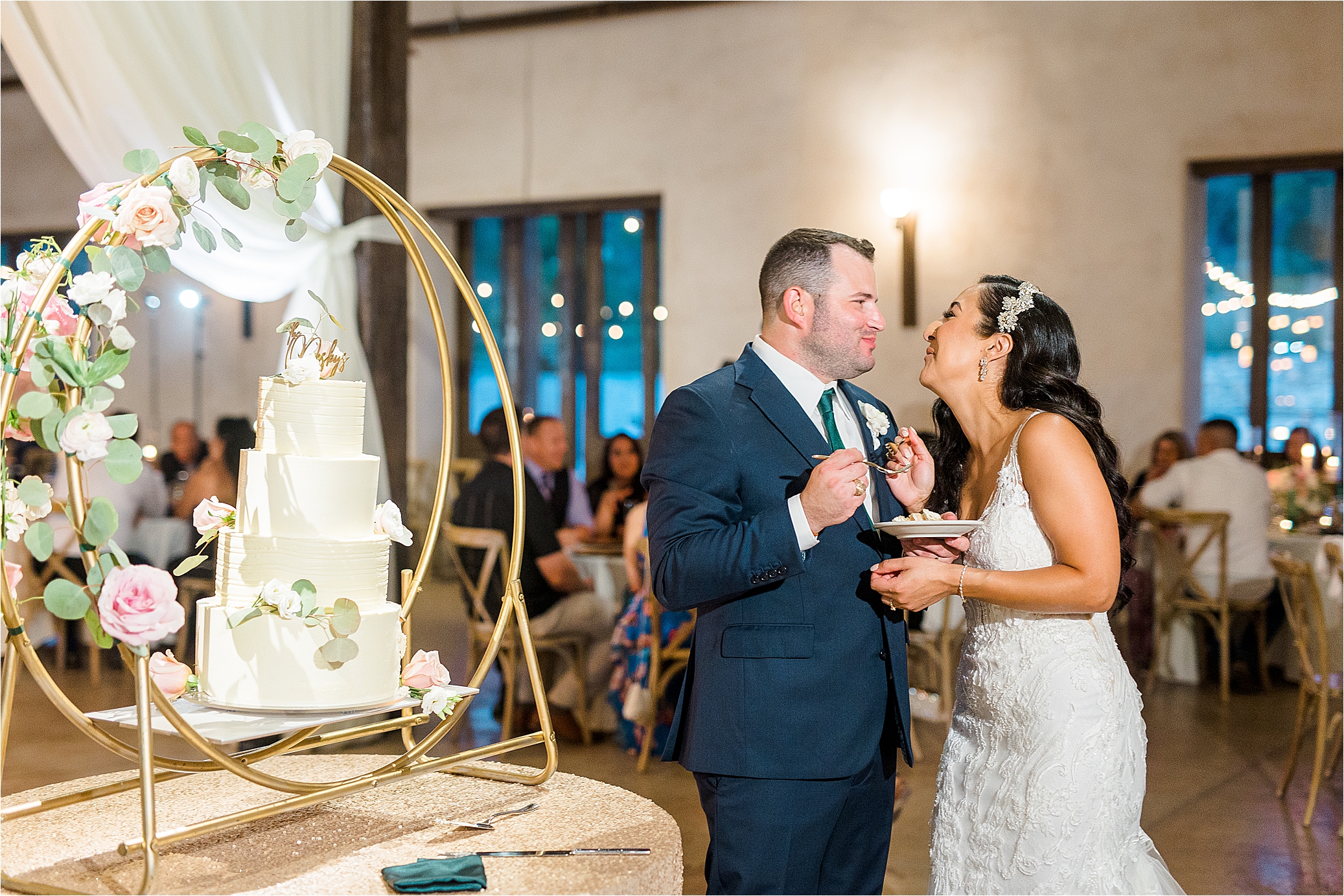 Newlyweds smile while they eat their wedding cake at Lost Mission Wedding reception 