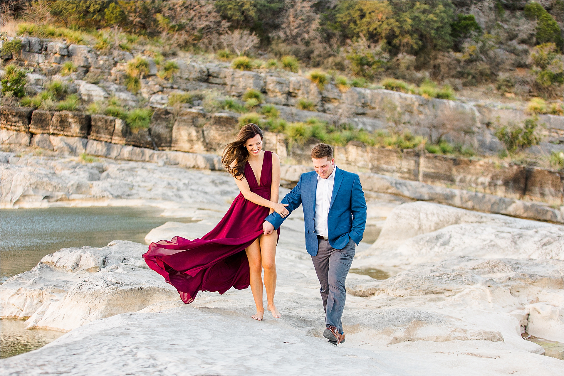 An engaged couple walks along the rocks as the wind blows during an Austin Texas Engagement Session at Pedernales Falls State Park 